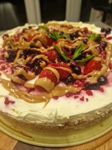 A whole berry cheesecake topped with strawberries, blueberries, mint and a caramel drizzle.