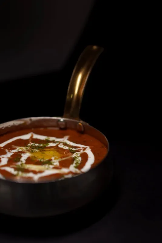 Dal makhani in a dark bowl, finished with a swirl of cream.