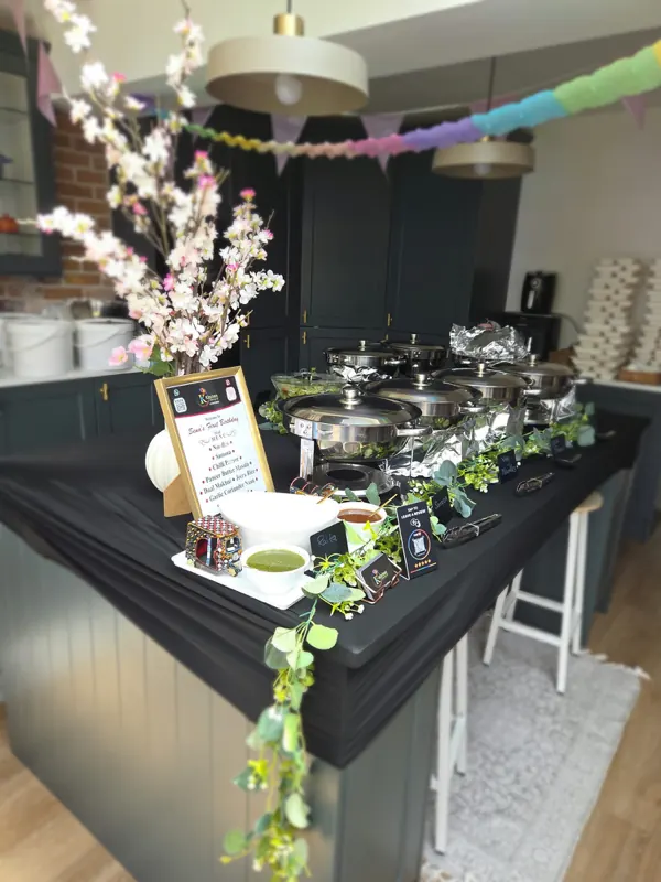 Krishna&rsquo;s setup at a house party: chafing dishes down the island, chutneys plated and a menu card standing at the end.
