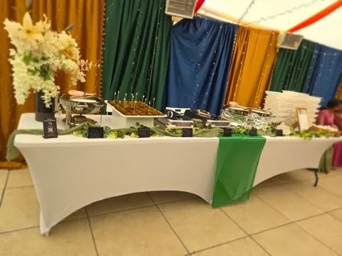 A long dressed buffet table we set up against coloured drapes at a wedding function.