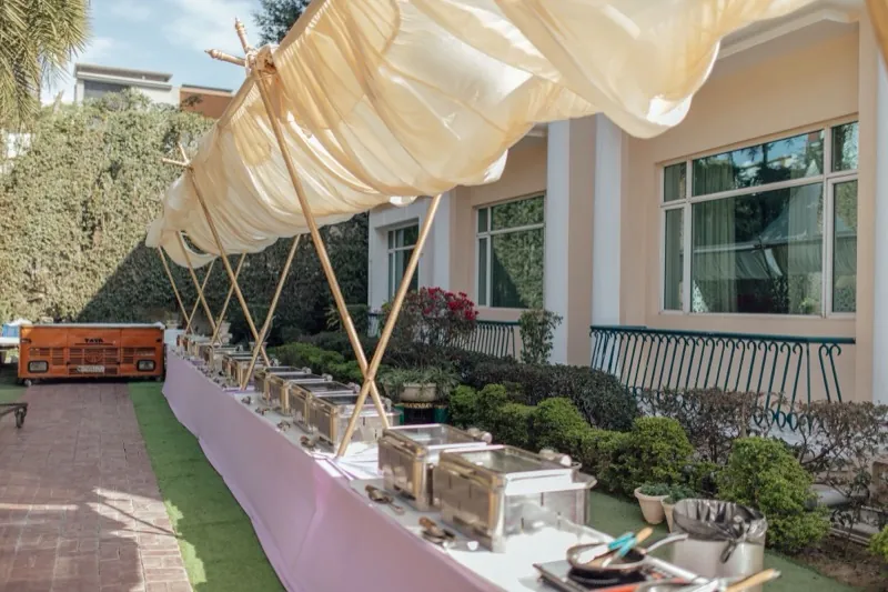 An outdoor catering line set up under a marquee canopy.