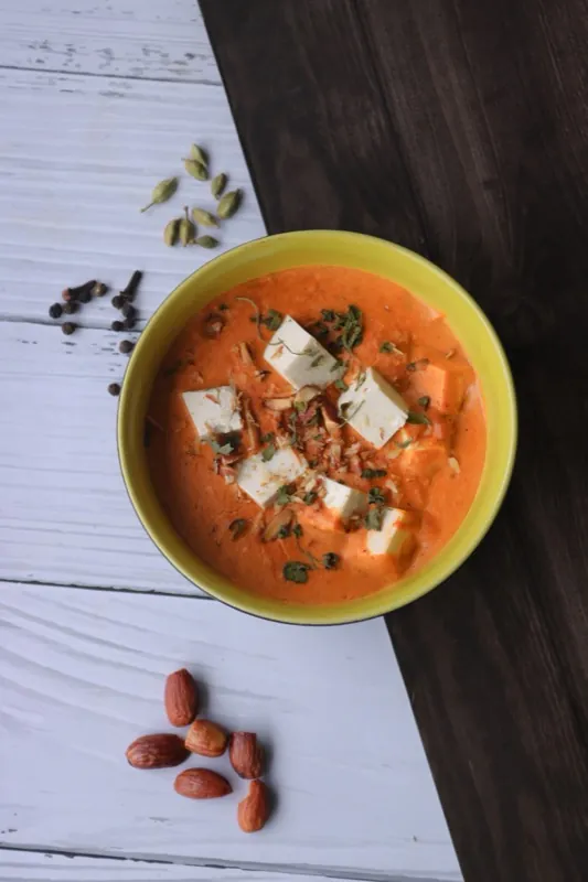 A creamy tomato paneer curry with the cubes of paneer clearly visible.