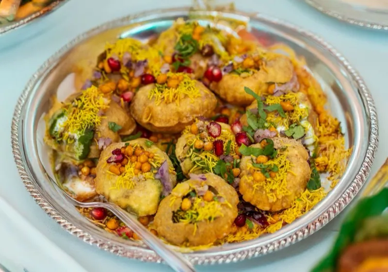 Pani puri served on a plate with sev and pomegranate.