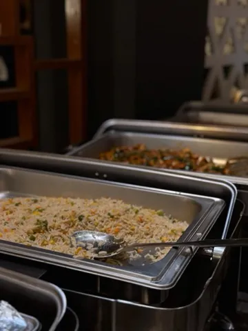 Catering trays of rice and a green vegetable dish.