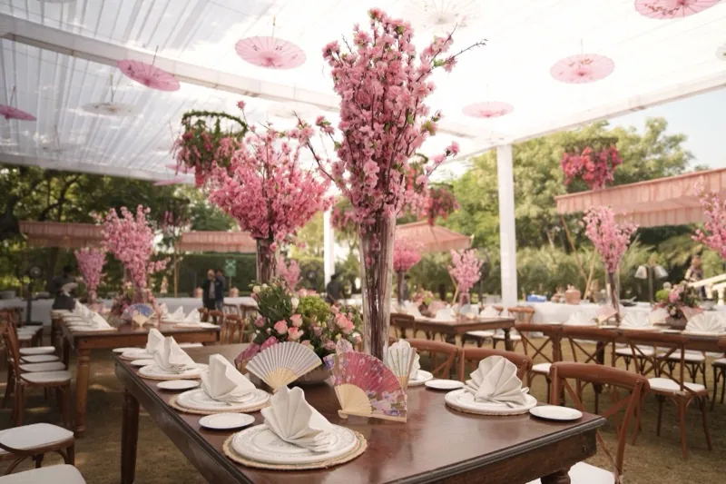 Long tables laid for a reception under a marquee, with tall centrepieces.